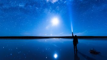 Immagine di una persona con una torcia in mano che punta verso il cielo