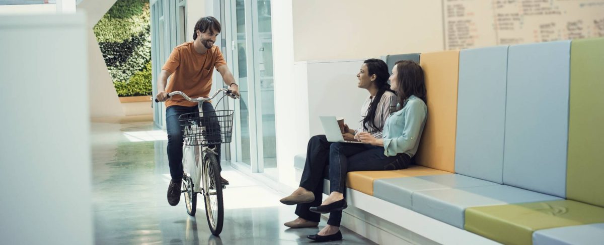 giovane professionista che si sposta in bicicletta in azienda per incontrare i colleghi
