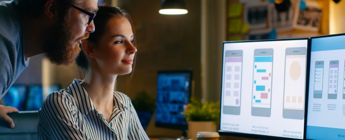 L’immagine che accompagna la News sulla partnership con Thought Machine ritrae una giovane donna, affiancata da un uomo, alla scrivania mentre osservano insieme gli schermi di un pc in cui sono visibili dei progetti relativi a servizi disponibili su smartphone.