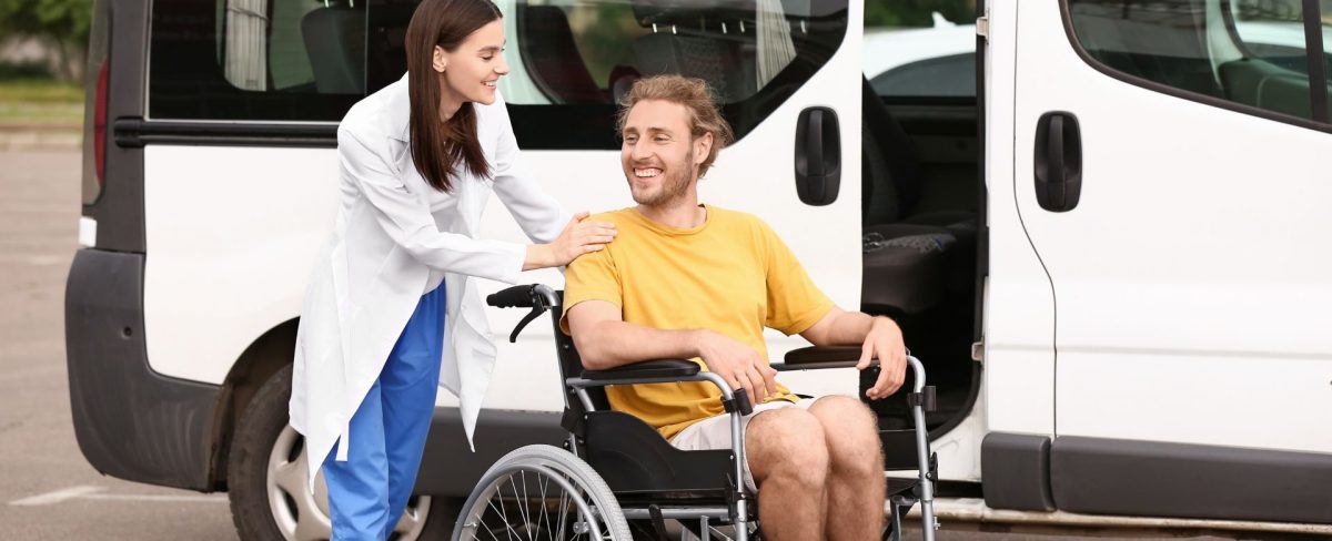 L’immagine che accompagna la news sulla valutazione dell’impatto sociale dei finanziamenti erogati alle organizzazioni non profit, ritrae un giovane sorridente in abiti informali in sedia a rotelle, accompagnato da una giovane donna con la quale sta dialogando, di fronte a un automezzo bianco adibito al trasporto di più persone