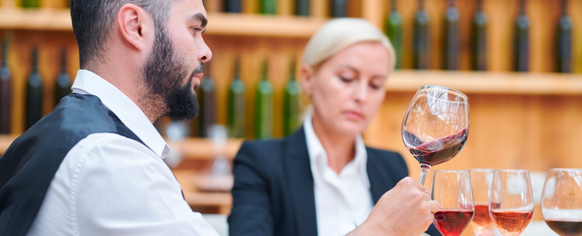 L’immagine che accompagna la News sulla partecipazione di Intesa Sanpaolo a Vinitaly 2024 con l’incontro “Filiere di internazionalizzazione. Le imprese agroalimentari italiane tra vecchi e nuovi mercati”, ritrae un giovane sommelier in camicia bianca e giacchino nero che regge un calice di vino rosso nell'atto di portarlo al naso per sentirne il profumo
