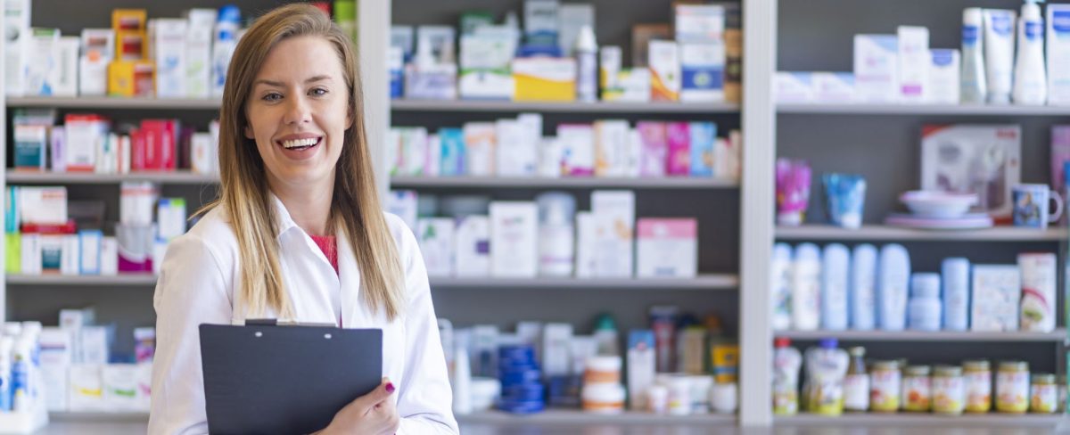 L’immagine che accompagna la News su Intesa Sanpaolo Partner Istituzionale della 25ª edizione delle Giornate di Raccolta del Farmaco, promossa dal Banco Farmaceutico, ritrae in primo piano una giovane farmacista sorridente in camice bianco e, sullo sfondo, degli scaffali ricolmi di prodotti farmaceutici