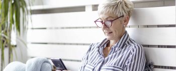 signora di meza età con occhiali che guarda il cellulare 